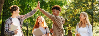 Zwei Teenager klatschen sich ab, ein Mädchen steht lächelnd dabei.