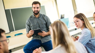 Young male teacher sitting in classroom
